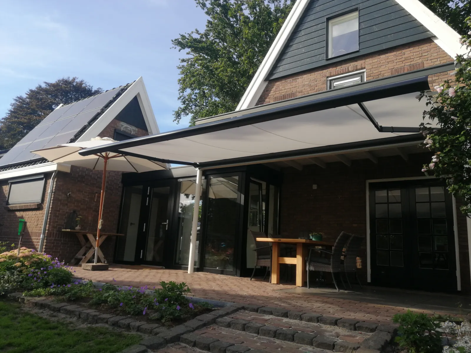 Crèmekleurig knikarmscherm boven een terras