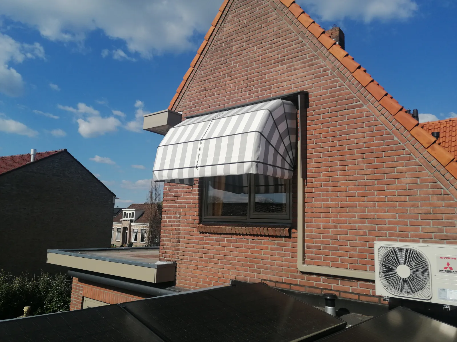 Grijs-wit gestreepte markies boven een raam