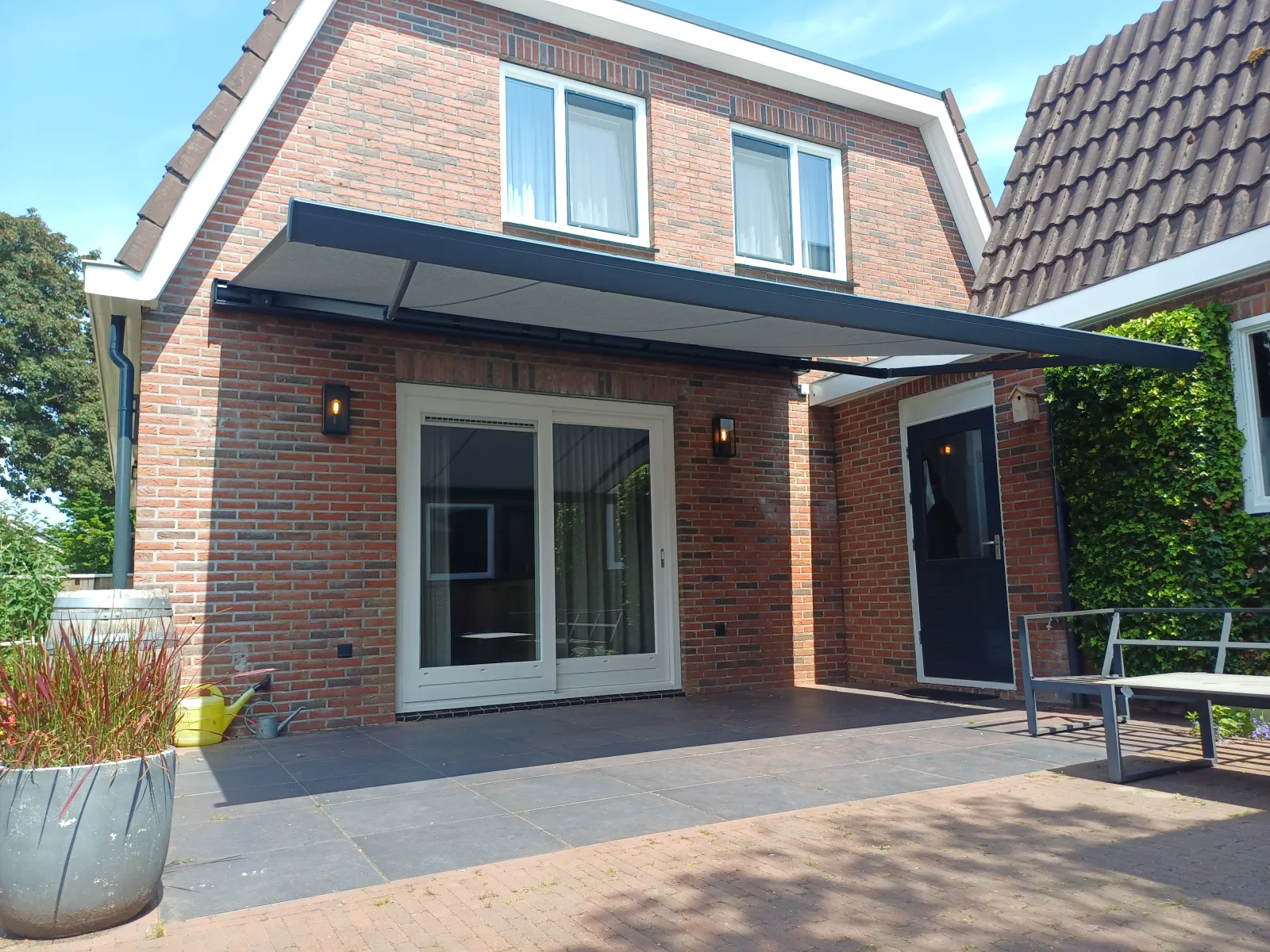 Knikarmscherm boven een terras met schuifpui